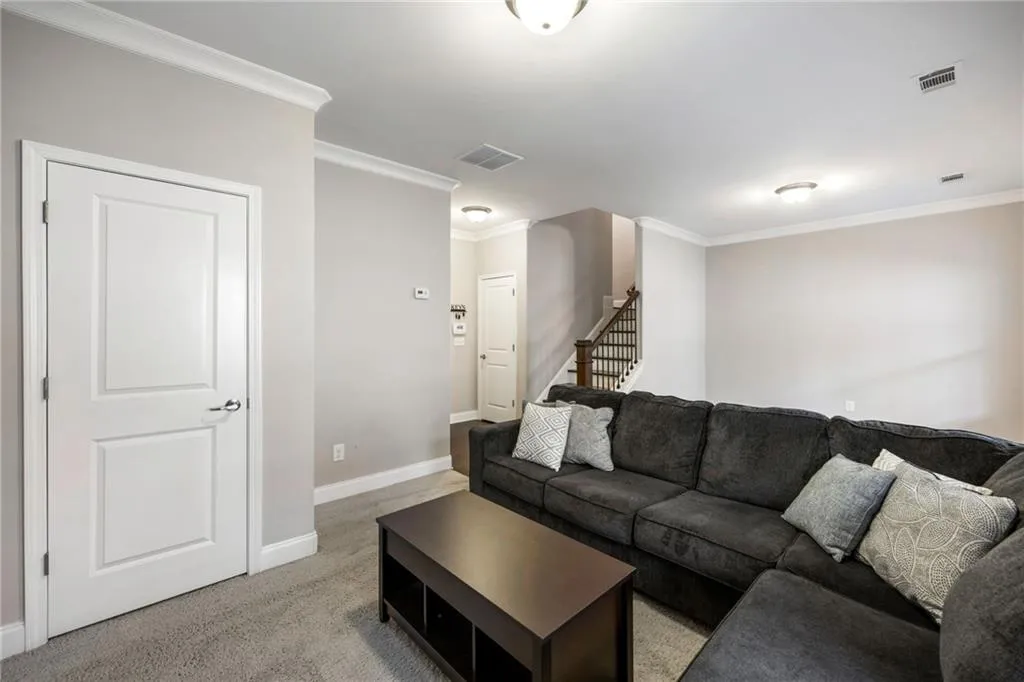 Living room featuring light colored carpet, ornamental molding, and stairway