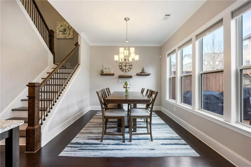 Dining area featuring dark wood-style floors, crown molding, stairway, and a chandelier