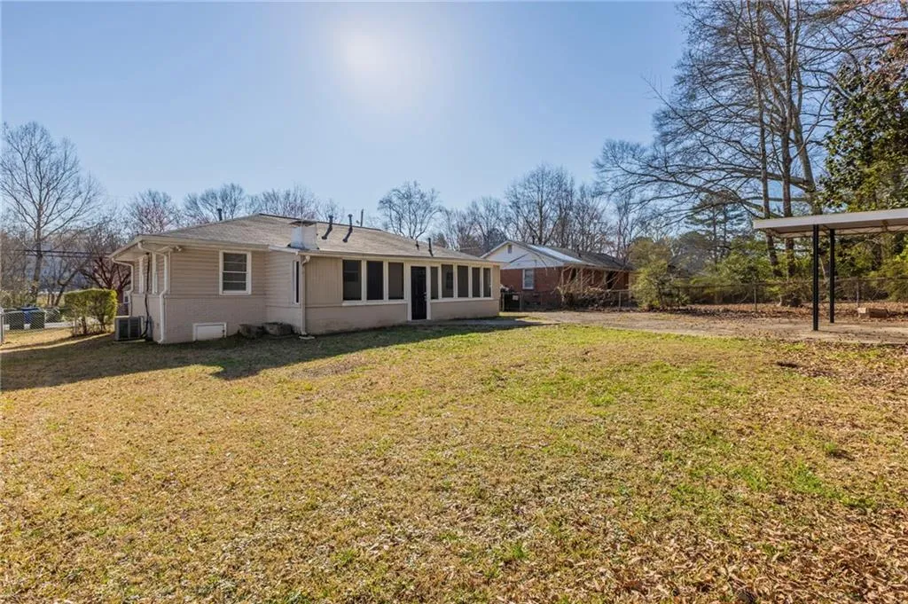 Rear view of house featuring fence, cooling unit, and a yard