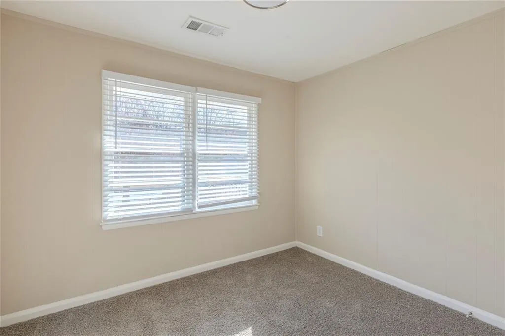 Empty room featuring carpet, visible vents, and baseboards