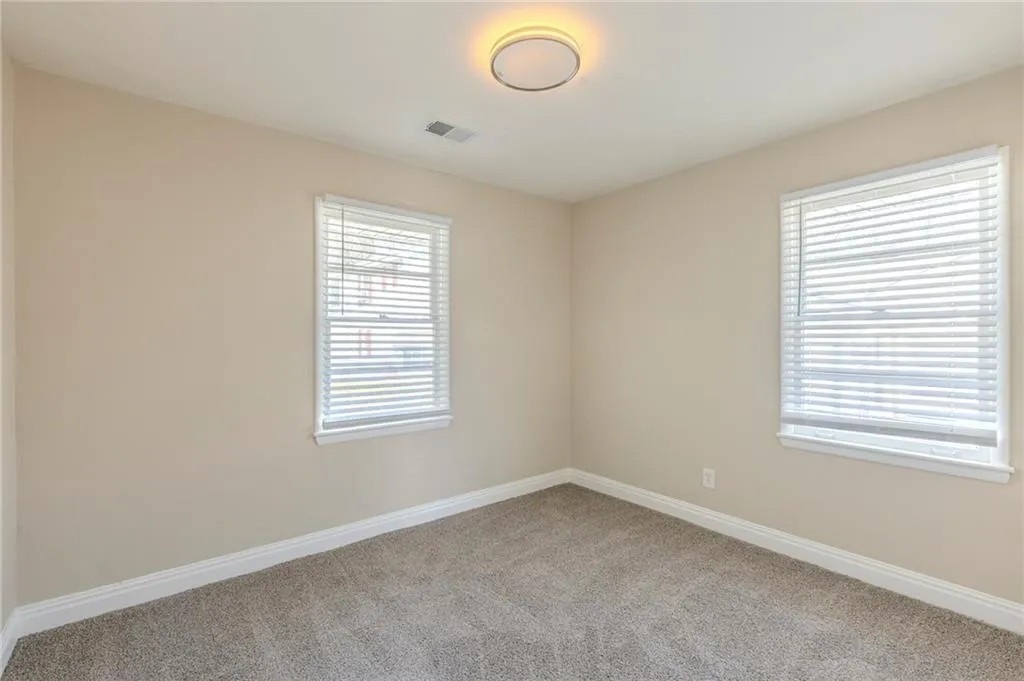 Carpeted empty room featuring baseboards and visible vents