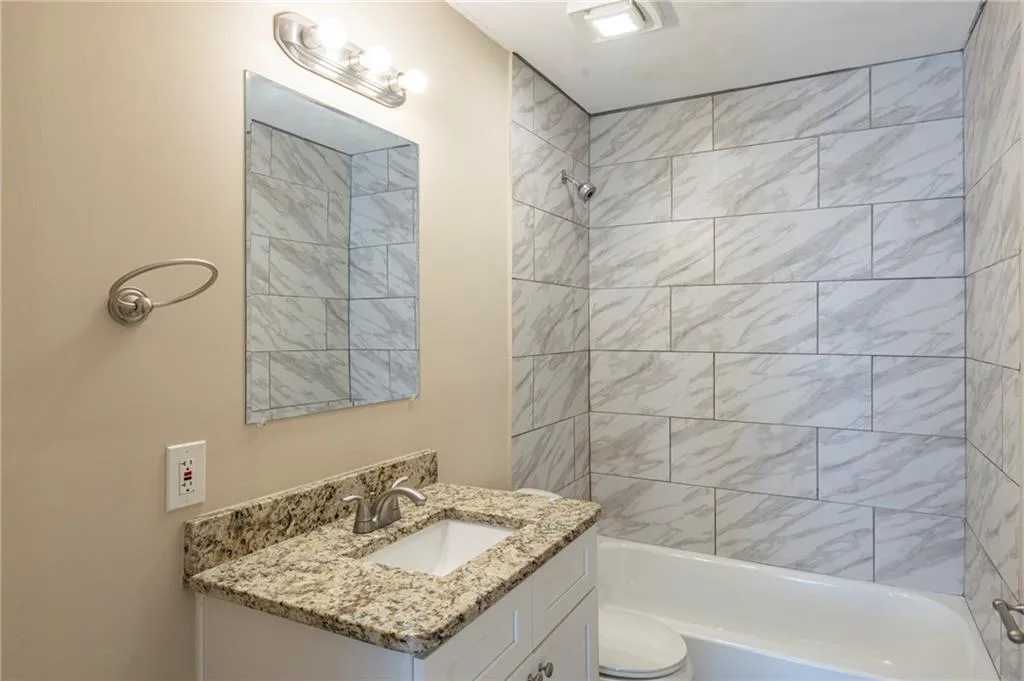 Bathroom featuring tub / shower combination, vanity, and toilet