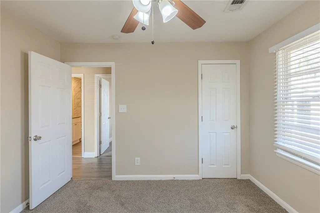 Unfurnished bedroom with carpet, multiple windows, baseboards, and visible vents