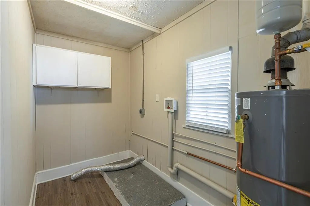 Laundry room with washer hookup, gas water heater, cabinet space, electric dryer hookup, and wood finished floors
