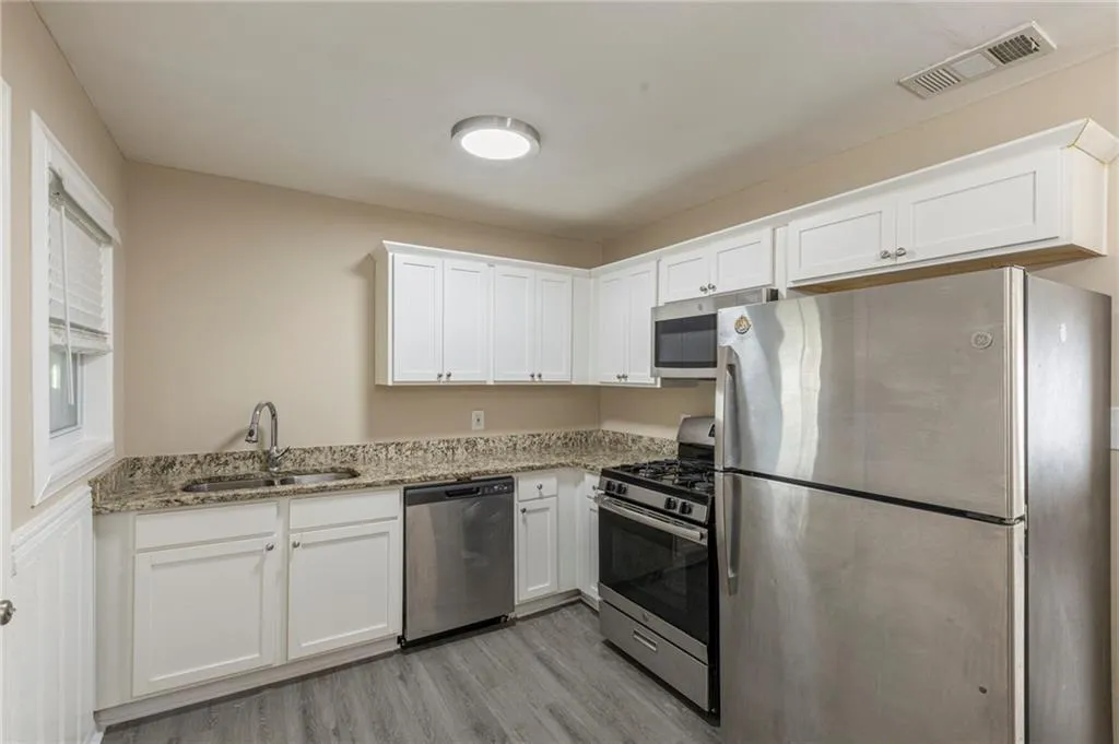 Kitchen featuring stainless steel appliances, a sink, visible vents, white cabinets, and light wood finished floors