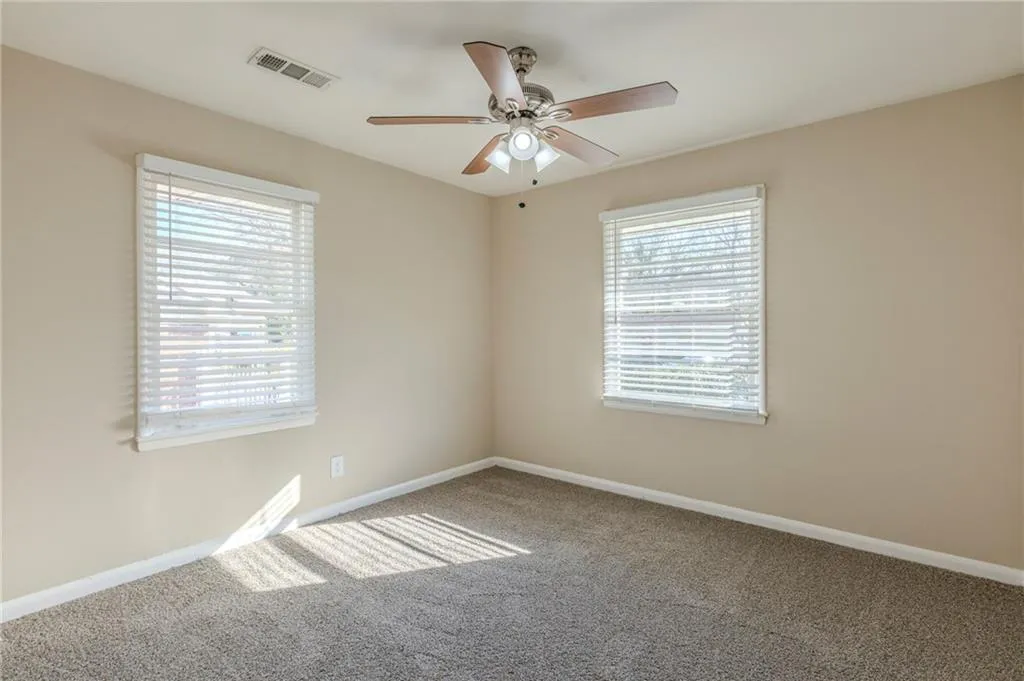 Spare room with plenty of natural light, visible vents, and carpet flooring