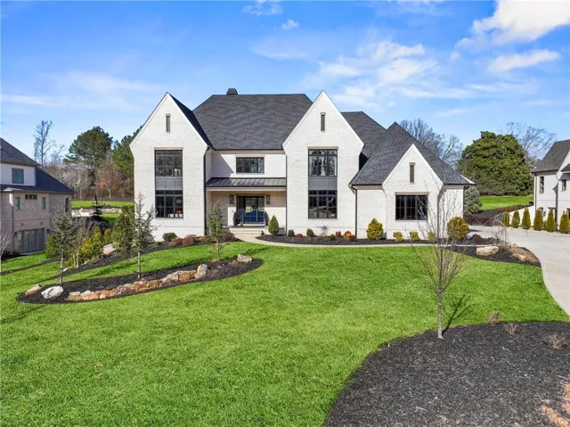 French provincial home featuring a front lawn, a standing seam roof, a metal roof, roof with shingles, and a chimney