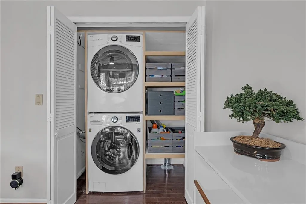Laundry area featuring dark wood-style floors and stacked washer / drying machine