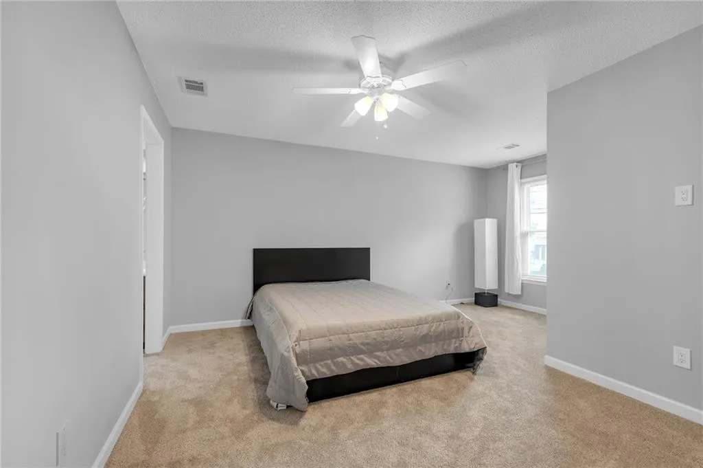 Bedroom featuring a textured ceiling, light carpet, and a ceiling fan