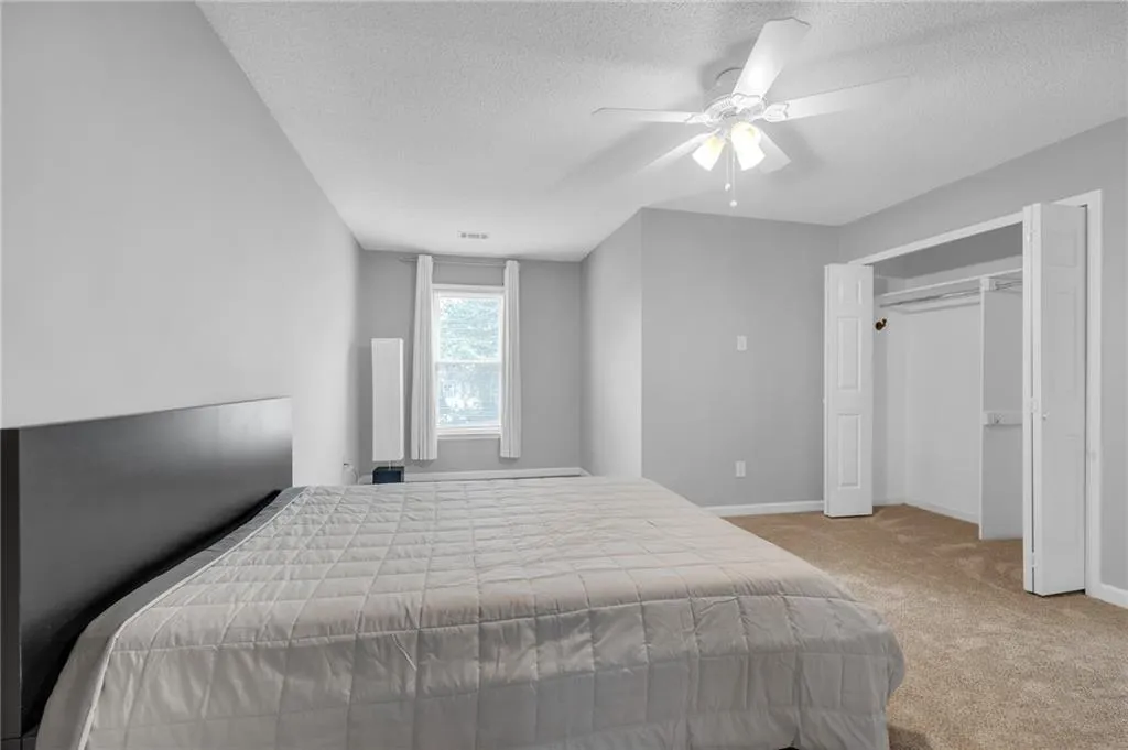 Bedroom featuring light carpet, a closet, a textured ceiling, and ceiling fan