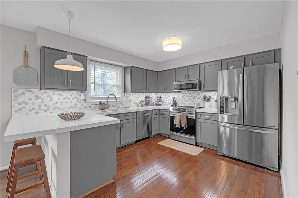 Kitchen with stainless steel appliances, tasteful backsplash, a kitchen bar, and hanging light fixtures
