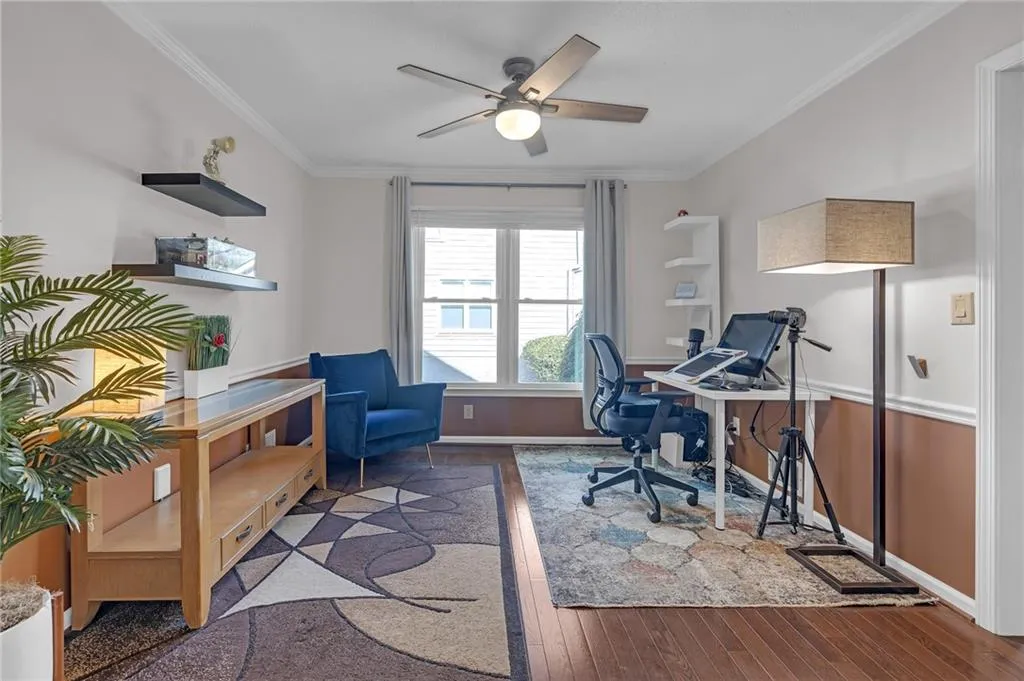 Office area featuring dark wood finished floors, crown molding, and a ceiling fan