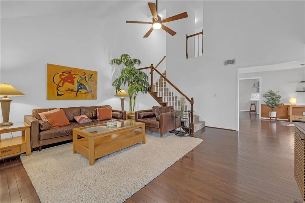 Living area featuring a ceiling fan, dark wood-type flooring, and a high ceiling