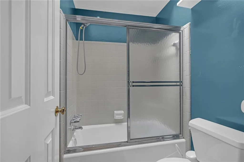 Bathroom with toilet and bath / shower combo with glass door