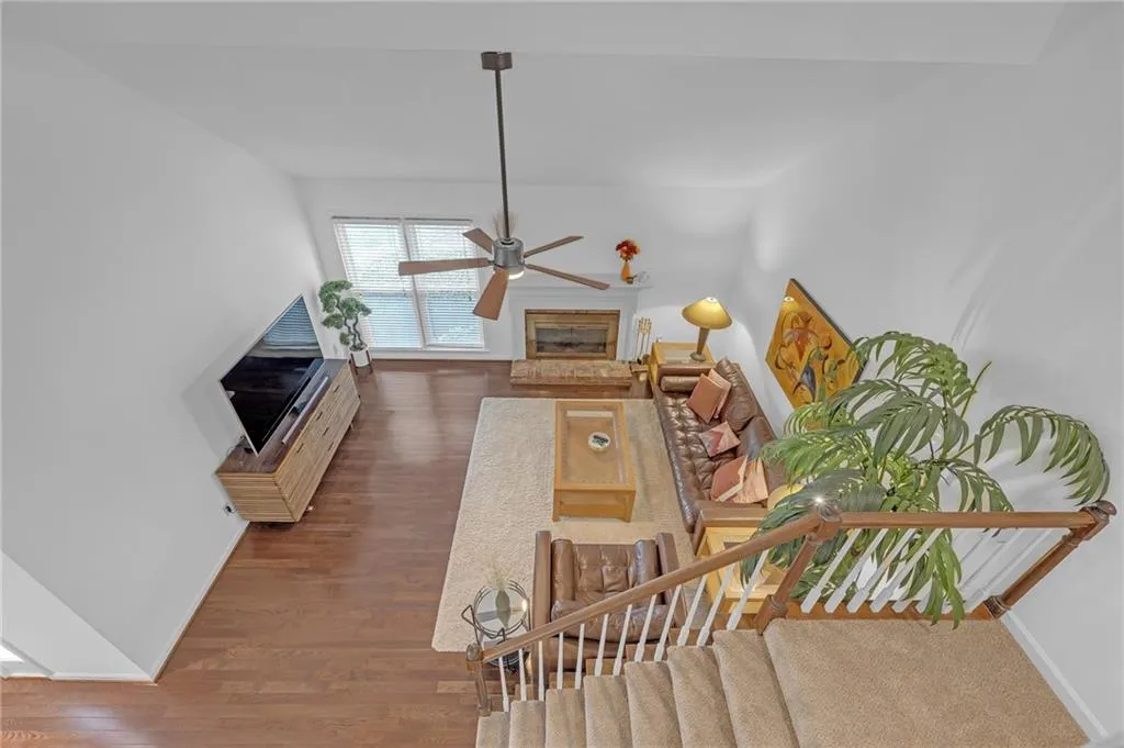Living area with a glass covered fireplace, dark wood-style floors, and ceiling fan