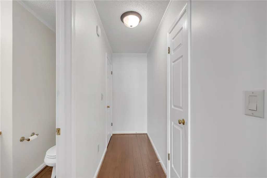 Hallway with hardwood / wood-style floors, ornamental molding, and a textured ceiling