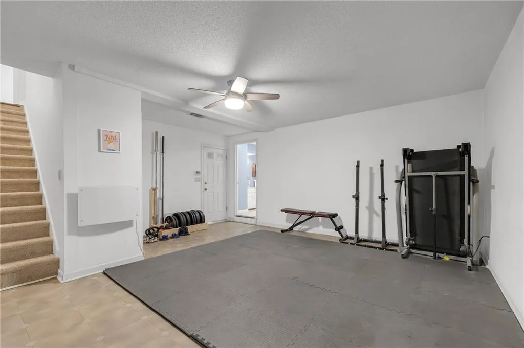 Workout room featuring ceiling fan and a textured ceiling