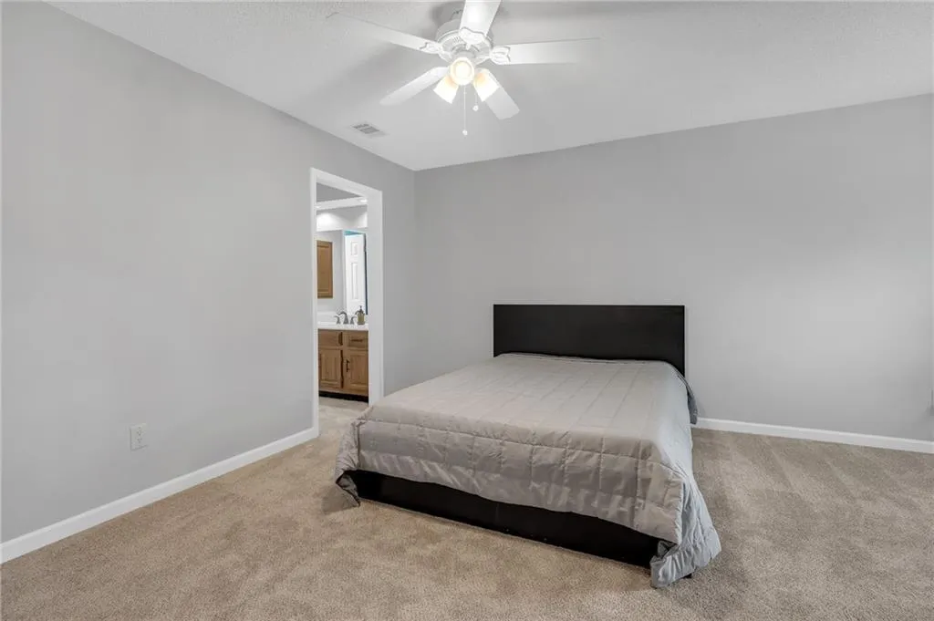 Bedroom featuring light carpet, a ceiling fan, and ensuite bathroom