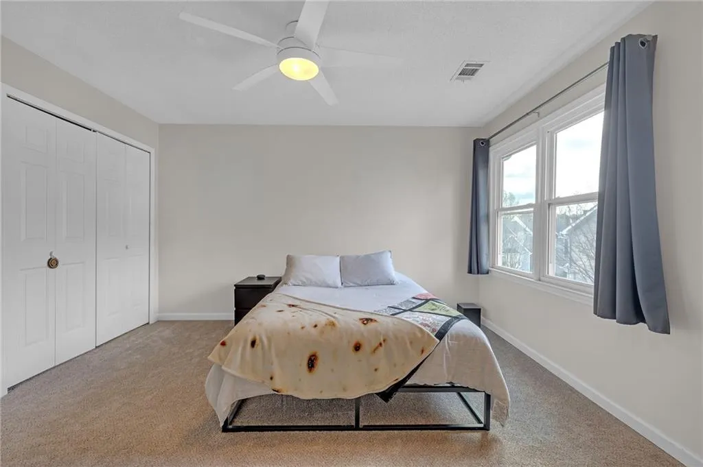 Carpeted bedroom featuring a closet and ceiling fan