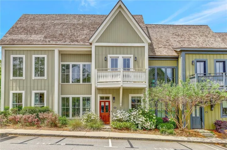 View of front of property with a balcony, board and batten siding, french doors, and uncovered parking
