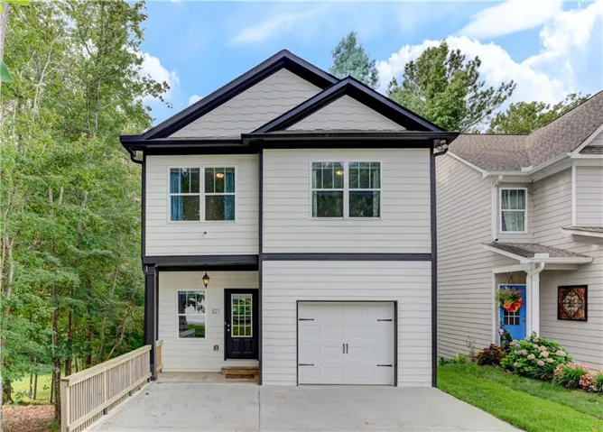 Modern exterior with light siding, dark trim, an attached garage, and a covered entry