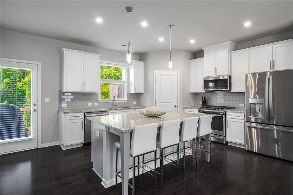 Kitchen featuring stainless steel appliances, a kitchen island, dark wood finished floors, a breakfast bar area, and white cabinetry