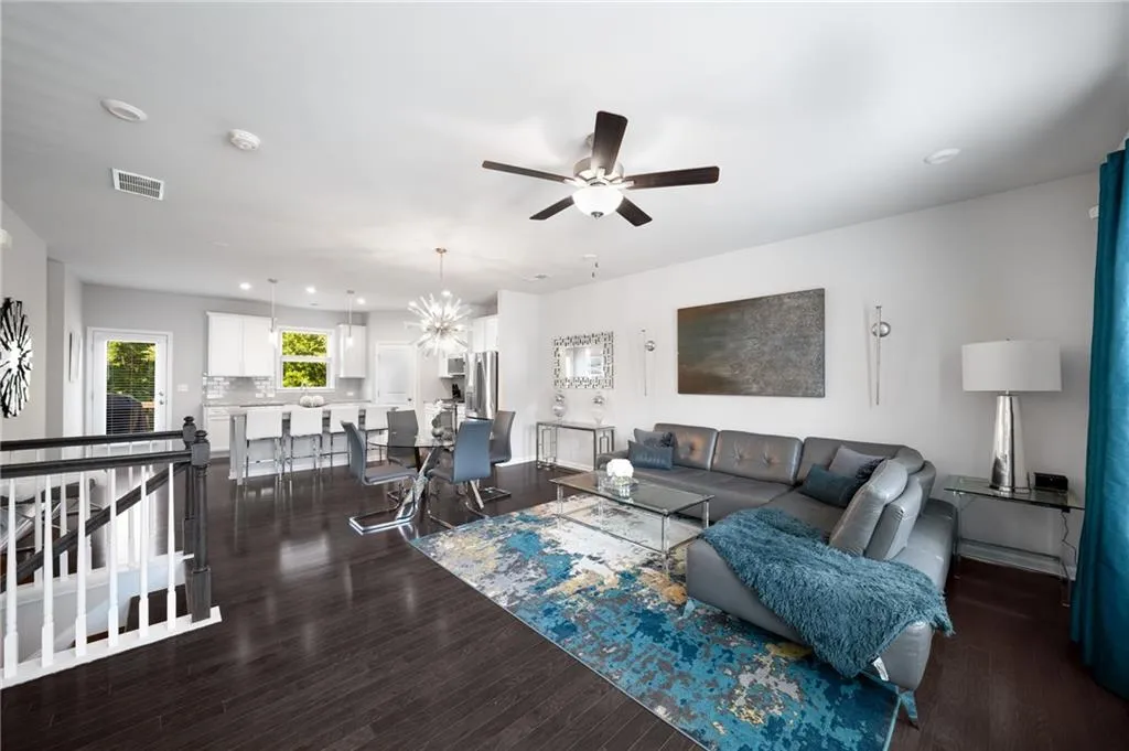 Living area with ceiling fan, dark wood-style floors, recessed lighting, and a chandelier