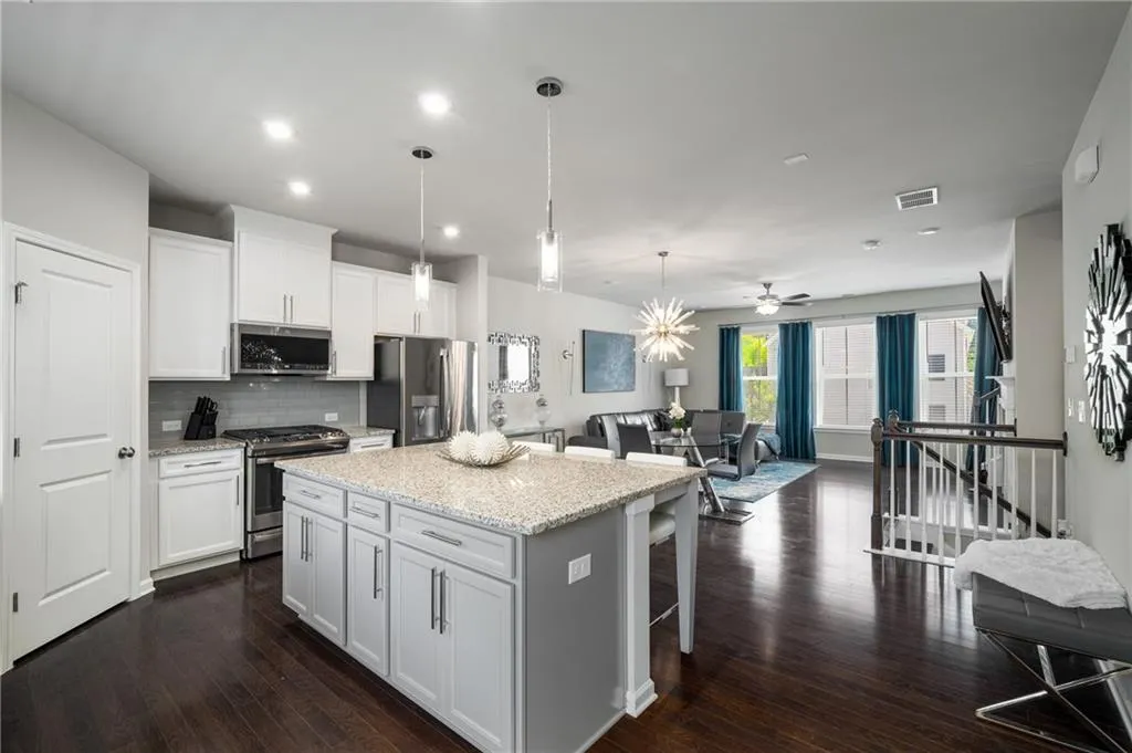 Kitchen featuring appliances with stainless steel finishes, open floor plan, a center island, tasteful backsplash, and white cabinetry