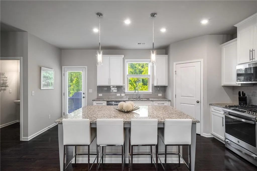 Kitchen featuring stainless steel appliances, a center island, tasteful backsplash, a kitchen breakfast bar, and white cabinets