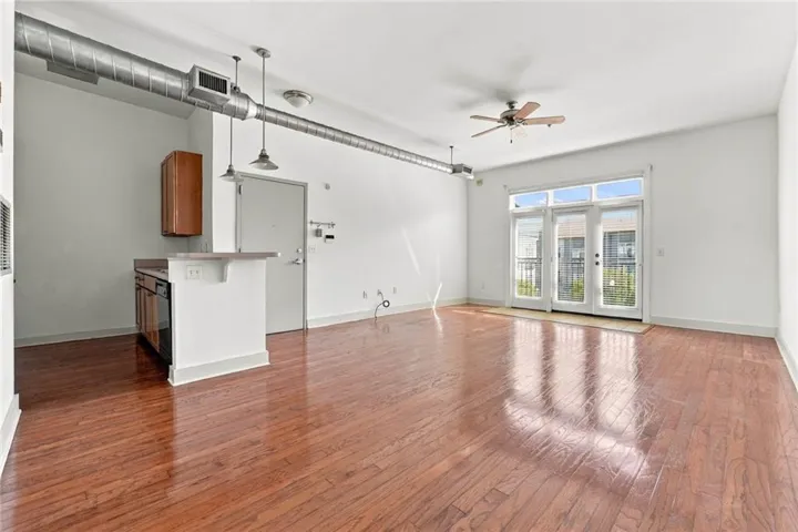 Hardwood flooring throughout, exposed ductwork, pendant lighting, kitchen peninsula with breakfast bar, and double French doors to an outdoor area