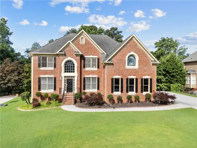 Brick exterior with black shutters and contrasting trim, featuring a prominent arched entry window and a gabled roofline