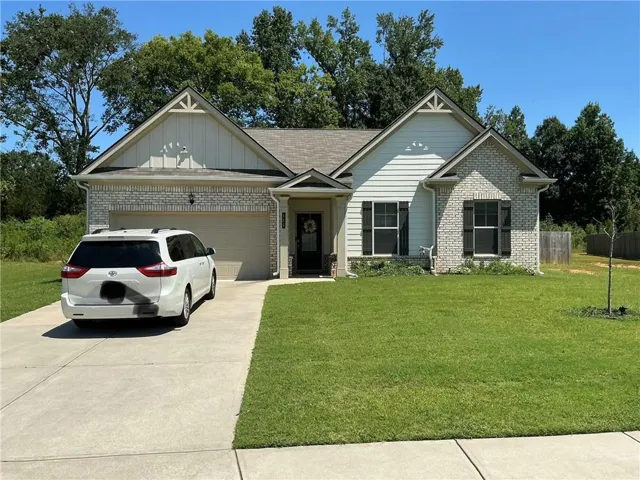 Exterior featuring a combination of light-colored brick and siding, a covered entry, an attached garage, a concrete driveway, and a maintained front lawn