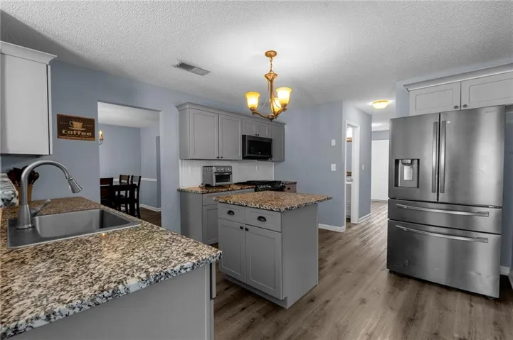 Kitchen featuring wood-finish flooring, an island with stone countertop, stainless steel appliances, and gray cabinetry