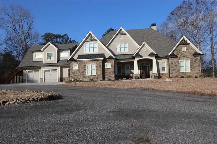 Craftsman-style house with stone siding, a standing seam roof, a chimney, and roof with shingles