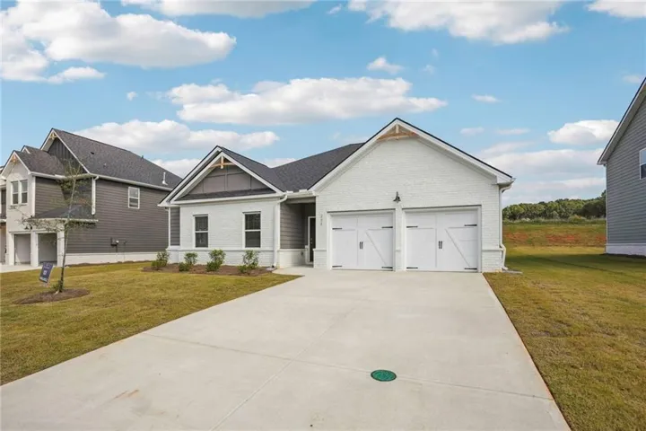 SAMPLE IMAGES Modern ranch-style home featuring a white brick and gray siding exterior, an attached two-car garage with carriage-style doors, a concrete driveway, and a manicured lawn