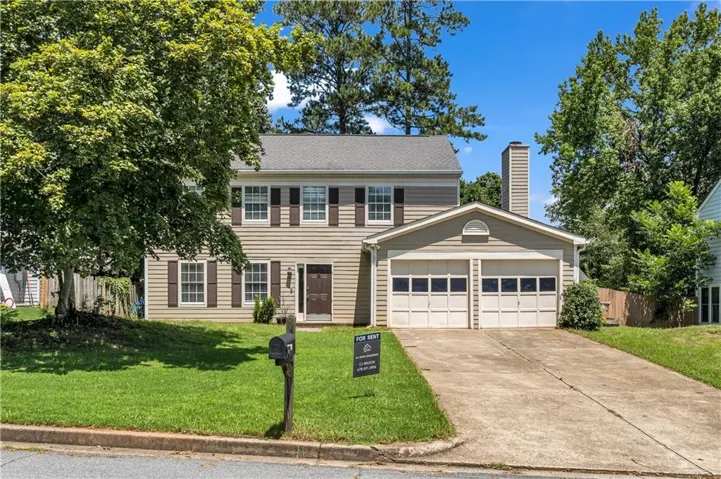 Two-story residence featuring light-colored siding, a two-car garage, and a concrete driveway