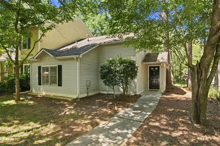 Siding exterior with a covered entry, dark paneled door, and a concrete walkway