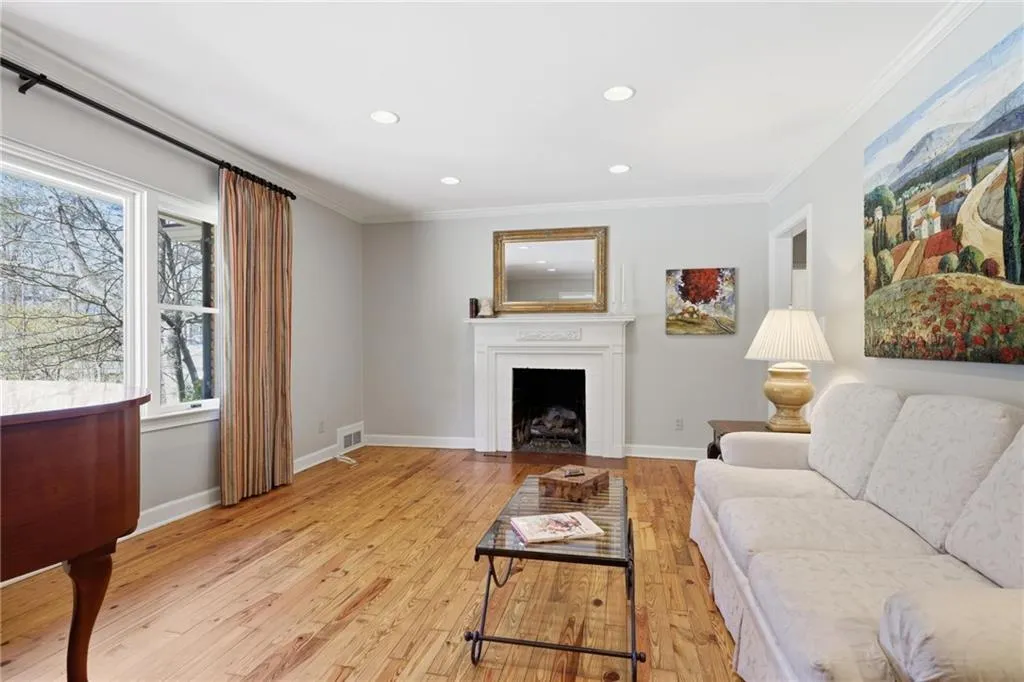 Living area with crown molding, light wood-style flooring, recessed lighting, and a fireplace