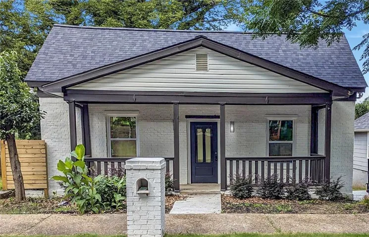 White brick exterior with a dark shingle roof