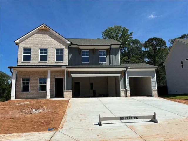 Two-story residence featuring light-colored brick and horizontal siding, a covered front entry with columns, and an integrated two-car garage