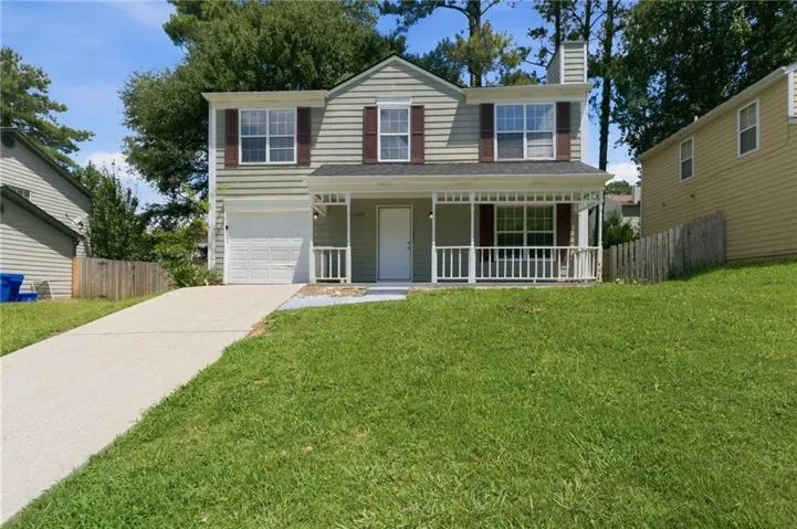 Two-story residence featuring light-colored siding, a covered front porch with white railing, and a single-car garage
