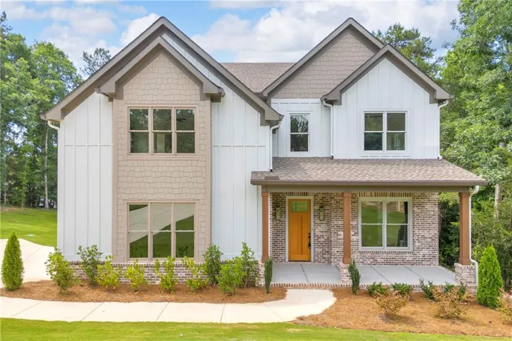 Two-story residence featuring a covered front porch with stone accents and wood posts