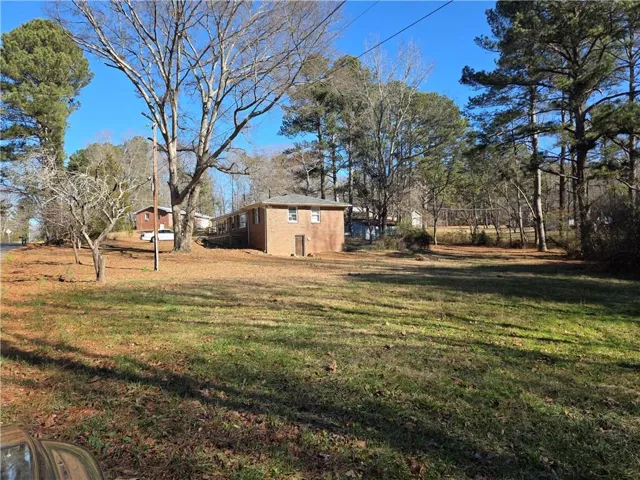 Expansive property featuring a brick residence, mature trees, and a spacious lawn