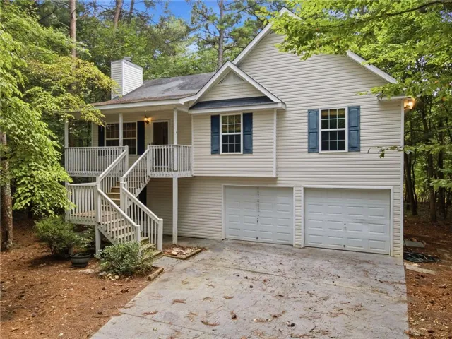 Charming elevated home featuring cream-colored vinyl siding, black shutters, and a welcoming front porch with white railings and curved staircase