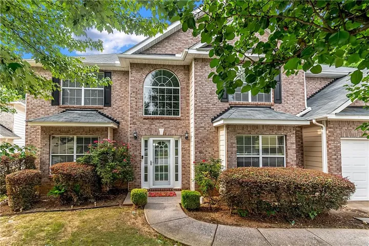 Brick facade with a white paneled front door, an arched transom window, and black shutters