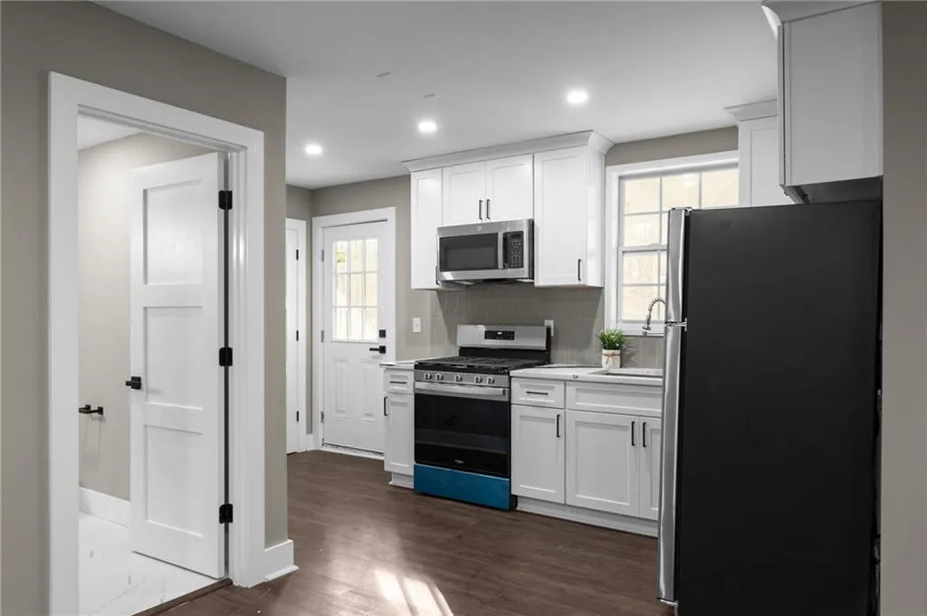 Kitchen with appliances with stainless steel finishes, light countertops, white cabinetry, backsplash, and recessed lighting
