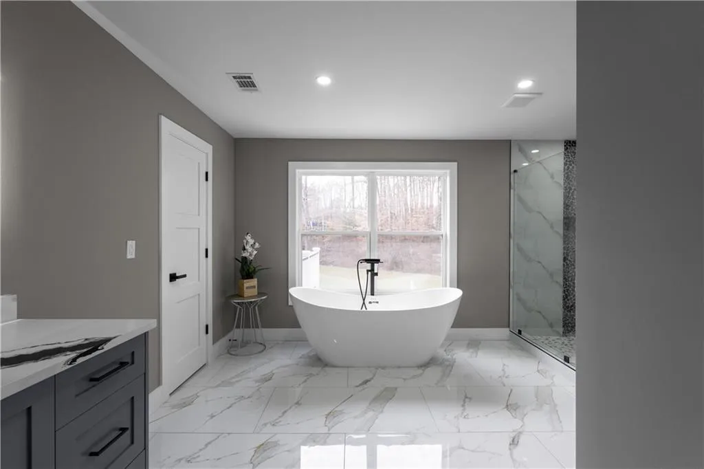 Bathroom with a freestanding tub, light marble finish floors, vanity, a marble finish shower, and recessed lighting