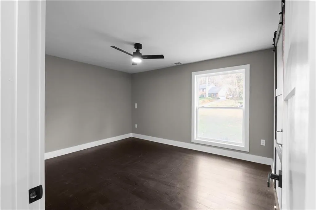 Unfurnished room with dark wood-type flooring and ceiling fan