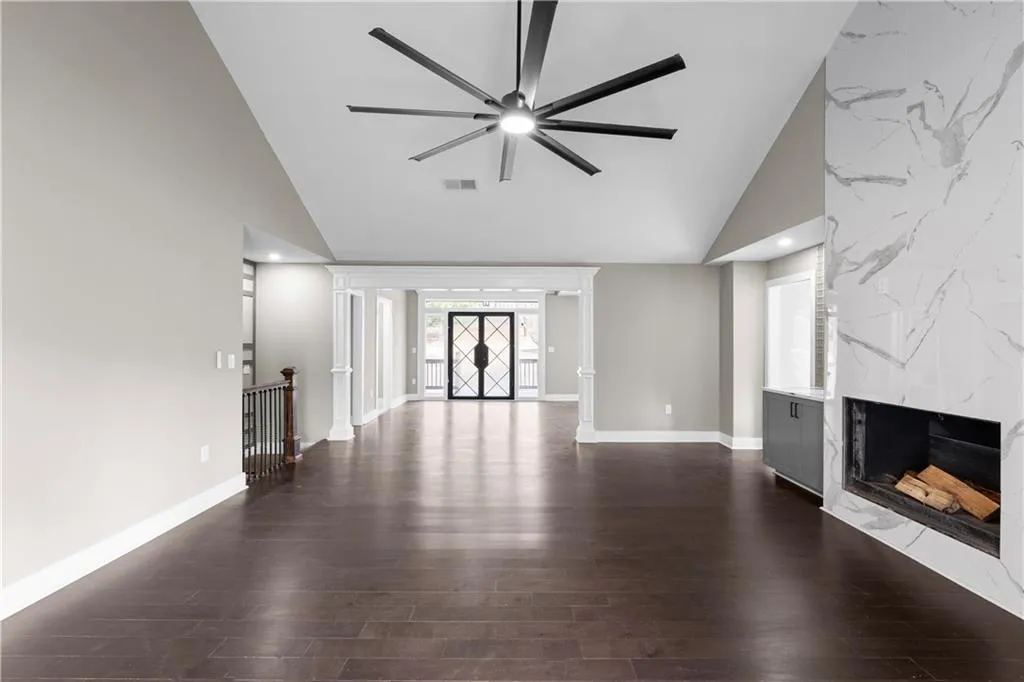Unfurnished living room with a fireplace, lofted ceiling, dark wood-style flooring, a ceiling fan, and recessed lighting