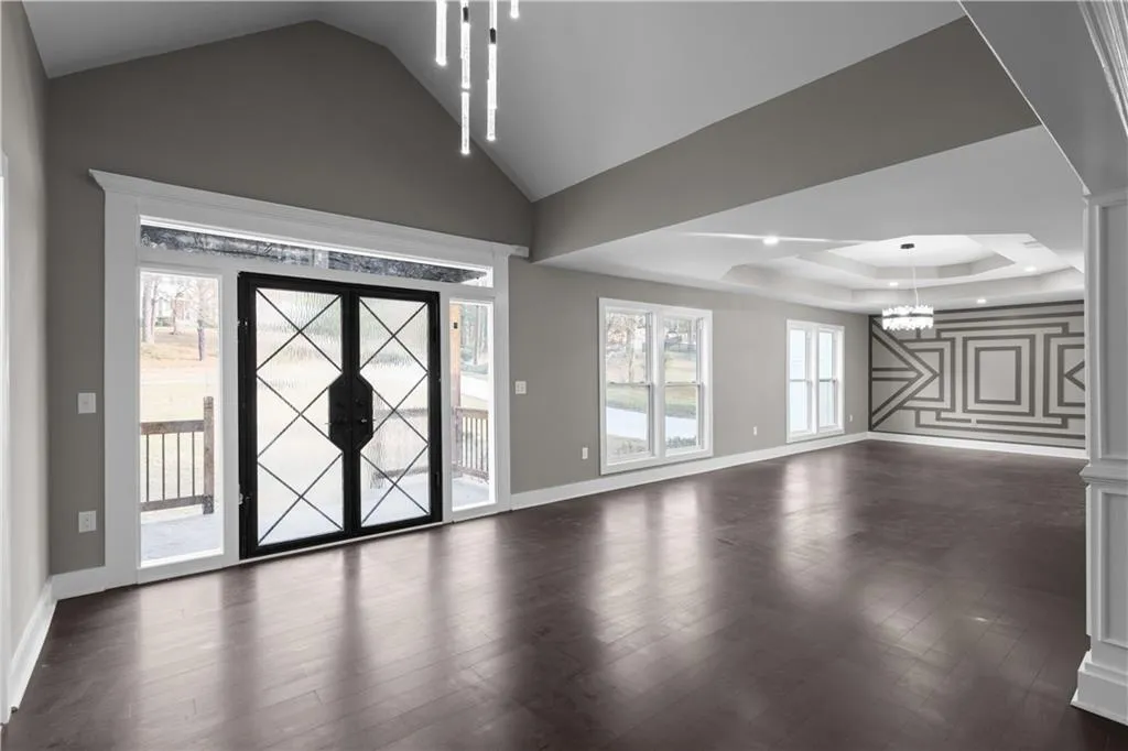 Foyer featuring lofted ceiling, dark wood-style floors, french doors, a chandelier, and a tray ceiling